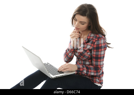 Young Woman seduto sul pavimento da solo utilizzando un computer portatile, lavorando da remoto a casa navigare su Internet, isolando da Coronavirus Foto Stock