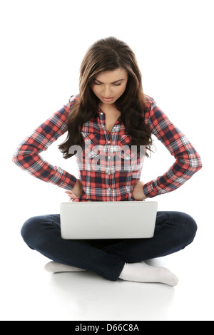 Young Woman seduto sul pavimento da solo utilizzando un computer portatile, lavorando da remoto a casa navigare su Internet, isolando da Coronavirus Foto Stock