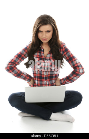 Young Woman seduto sul pavimento da solo utilizzando un computer portatile, lavorando da remoto a casa navigare su Internet, isolando da Coronavirus Foto Stock