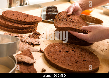 Pastry chef di tagliare il pan di spagna a strati. Torta di processo di  produzione Foto stock - Alamy