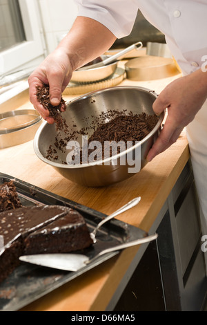 Lo Chef decorare la torta al cioccolato con il marrone scuro di zucchero a velo Foto Stock