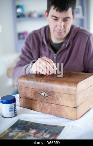 Uomo di mezza età a un tavolo da cucina ripristina un antico stile vittoriano pendenza di scrittura pronti a vendere ad una asta o negozio di antiquariato Foto Stock