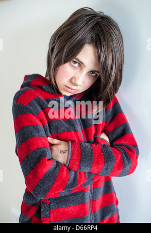 Giovane ragazza bianca dai capelli scuri che guarda triste, arrabbiata, vulnerabile e sconvolto, guardando la macchina fotografica e lontano dalla macchina fotografica che indossa una felpa rossa e grigia Foto Stock