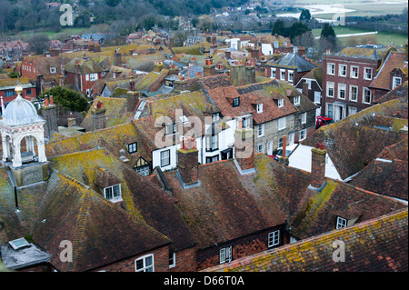 Di muschio verde tetto di tegole rosse e piani in cinque antico porto di segale in East Sussex con un fiume di distanza dalla torre della chiesa Foto Stock
