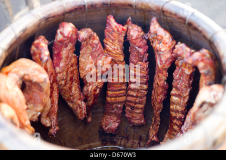 Affumicato grigliato costolette di maiale e di pollo. Cucinato in una canna di argilla in Thailandia mercato. Foto Stock