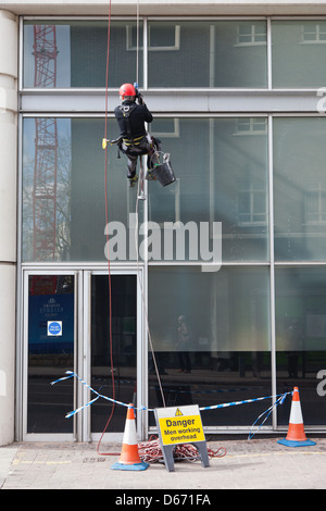 Detergente per vetri di indossare attrezzature di sicurezza pulizia di un moderno edificio aziendale Foto Stock