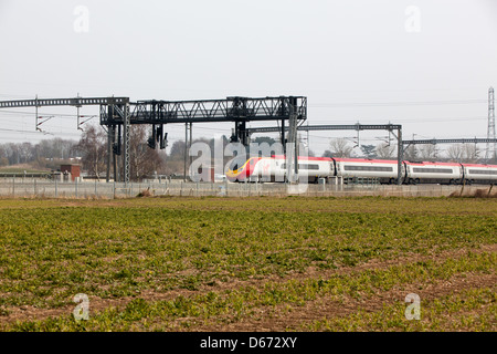 Una vergine treno passa sotto un gantry segnali sulla costa ovest Mainline. Foto Stock