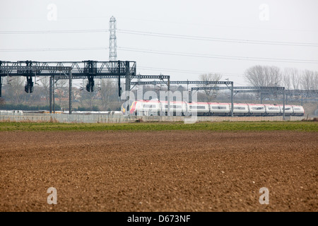 Una vergine treno passa sotto un gantry segnali sulla costa ovest Mainline. Foto Stock