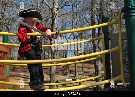 Un bambino appoggiato sulle corde di un parco giochi in nave Foto Stock