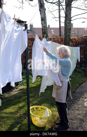 Anziano pensionato appendere fuori una linea di lavaggio sulla sua linea di lavaggio in aprile. Foto Stock