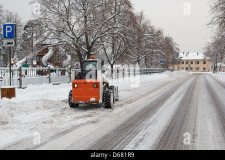Piccolo escavatore Bobcat lavorando sulla strada, pulizia neve Foto Stock