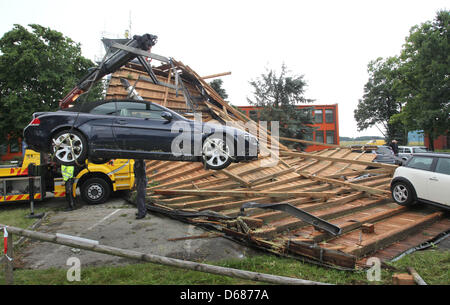 I dipendenti di auto Servizio di traino recuperare un auto dalle macerie di un tetto a Memmingen, Germania, 06 luglio 2012. Forti tempeste aveva portato via il tetto di un edificio amministrativo a Memmingen airport, che poi danneggiato diverse vetture. Foto: Karl-Josef Hildenbrand Foto Stock