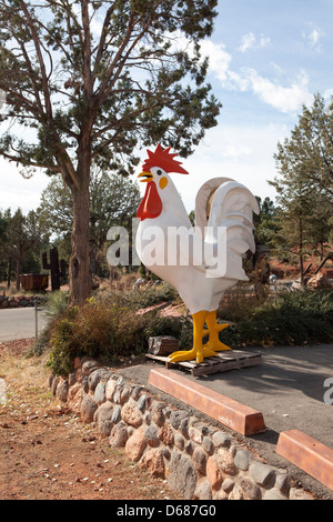 Un gallo figura accanto a una strada e le rocce rosse nel contesto, Sedona, in Arizona, Stati Uniti d'America Foto Stock