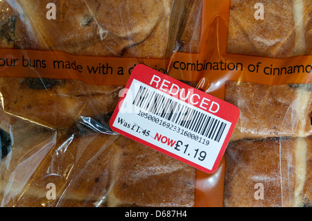 Un adesivo di ridotta su un pacchetto di supermercati di Hot Cross ciambelle. Foto Stock
