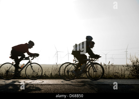 I ciclisti passando il piccolo Cheyne corte per centrali eoliche a Romney Marsh, Kent. Vicino alla East Sussex confine. Inghilterra, Regno Unito Foto Stock