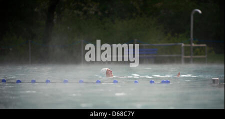 FILE - Un archivio foto datata 13 aprile 2012 mostra una donna nuotare nella piscina riscaldata piscina all'aria aperta Hausen in Frankfurt Main, Germania. Le perturbazioni atmosferiche in Hesse è stato negativo per le imprese - i giardini zoologici, piscine all'aperto e gelaterie lamentano un minor numero di visitatori rispetto al solito. In alcuni luoghi il numero di visitatori è diminuito di un terzo. Le speranze di tutti riposano ora sulla somma Foto Stock