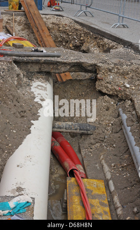 Scavo per lavori in corso durante la posa in opera di un condotto per la fibra ottica e cavi elettrici Foto Stock