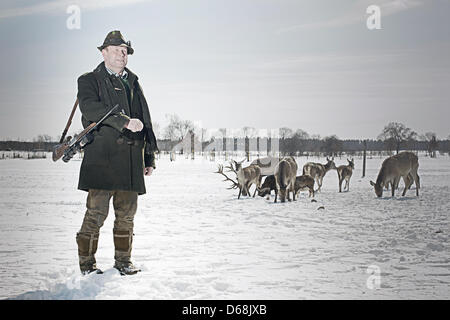 Il cacciatore Wolfgang Wernicke sorge su un campo. Sullo sfondo sono diversi cervi e daini. Foto Stock