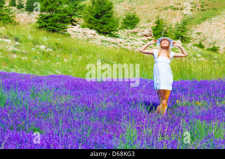 Donna attraente con gli occhi chiusi godendo luminoso caldo sole di luce, di trascorrere del tempo sulla bella fresca campo di lavanda Foto Stock