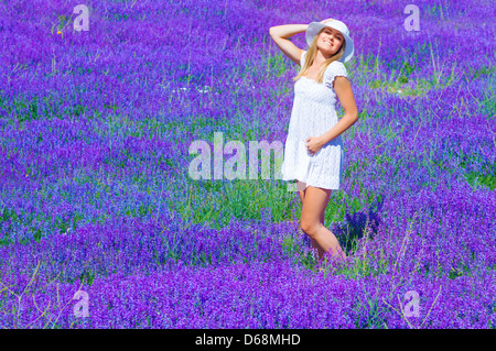 Pretty girl abbronzatura in lavanda glade, godendo di forte luce solare e fiori viola paesaggio, avendo divertimento all'aperto in estate Foto Stock