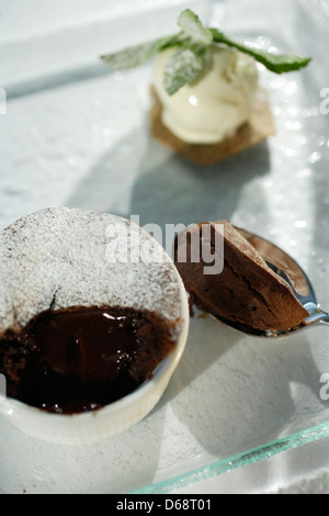 Smerigliato alci cioccolato dessert in un bianco ramekin su una lastra di vetro con gelato alla vaniglia convogliatore Foto Stock