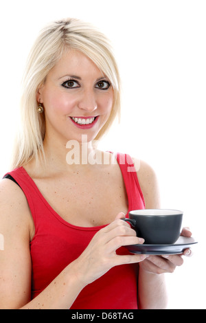 Fiducioso felice giovane donna bionda, rilassante, bere il tè o il caffè, indossando il colore rosso brillante Vest alto, isolato sfondo bianco con tracciato di ritaglio Foto Stock