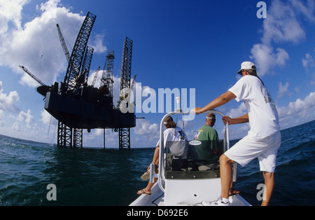 Gli uomini trolling e pesca nelle vicinanze di un impianto di trivellazione petrolifera piattaforma di perforazione nel Golfo del Messico al largo da Port Aransas Texas Foto Stock