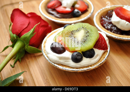 Mini torte alla frutta con una rosa rossa Foto Stock