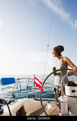 Donna sorridente dello sterzo sulla barca Foto Stock