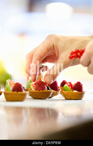 Baker rendendo crostate di frutta in cucina Foto Stock