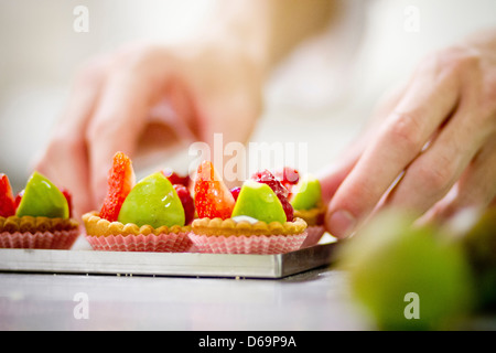 Baker rendendo crostate di frutta in cucina Foto Stock