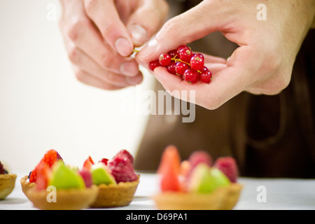 Baker rendendo crostate di frutta in cucina Foto Stock