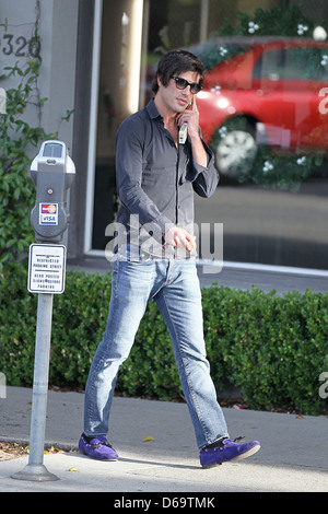 Brandon Davis fumatori e parlando sul suo telefono cellulare in Beverly Hills Los Angeles, California Foto Stock