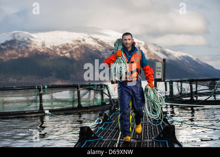 Lavoratore sull allevamento di salmoni nel lago rurale Foto Stock