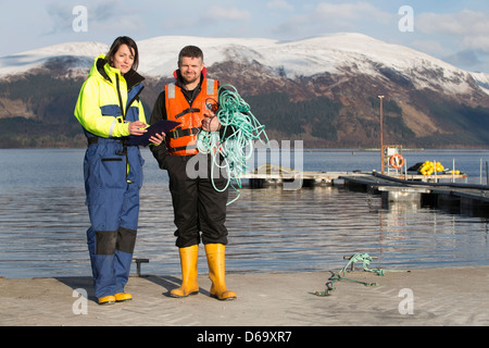 Lavoratori su allevamento di salmoni nel lago rurale Foto Stock