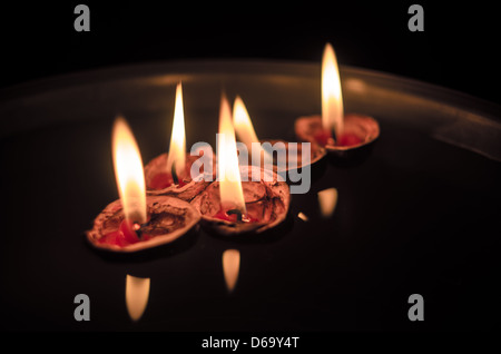 I gusci di noce con acceso candele galleggianti in una tazza di acqua Foto Stock