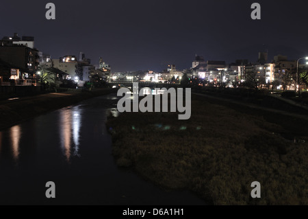 Una foto notturna del fiume Kamogawa a Kyoto, Giappone, che mostra l'acqua tranquilla e le luci della città. Questa scena cattura l'atmosfera tranquilla della passeggiata sul fiume di notte. Foto Stock