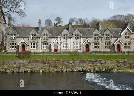 Sleddall gli ospizi di carità, sulla strada Aynam, Kendal e fiume Kent, Cumbria, Regno Unito Inghilterra, con Kendal Castle in background Foto Stock