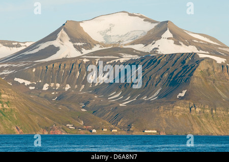 La Norvegia, l'arcipelago delle Svalbard, Spitsbergen, Isfjorden, Hiorthhamn. Cabine a bordo del ghiacciaio scolpito insummer montagne. Foto Stock