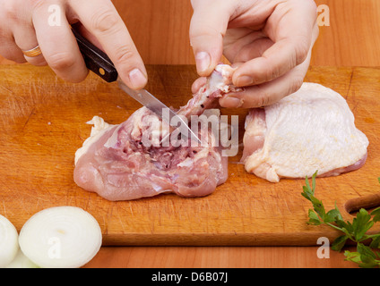 La cottura di cosce di pollo con un chop. Separazione delle ossa della coscia Foto Stock