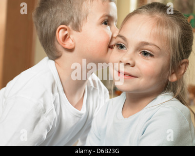 Ragazzo whispering in ragazze orecchio Foto Stock