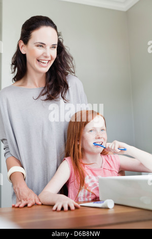 Madre guarda la figlia spazzola denti Foto Stock