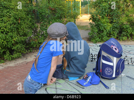 Illustrazione - un giovane ragazzo si siede su un tavolo da ping-pong accanto alla sua borsa scolastici e gioca con la sua smart phone, mentre una ragazza di orologi in Berlino, Germania, 22 agosto 2012. Foto: Jens Kalaene - Modello rilasciato Foto Stock