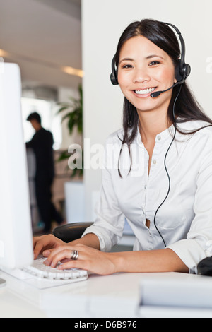 Imprenditrice che indossa la cuffia alla scrivania Foto Stock