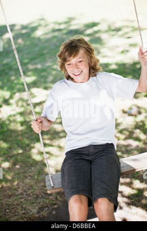 Ragazzo giocando su swing in posizione di parcheggio Foto Stock