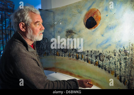 Il vetro designer Werner Kothe mostra una delle sue opere, un vetro piegato lastra verniciata con un paesaggio in Annenwalde, Germania, 19 dicembre 2011. Fino al 1865, il vetro era stata prodotta presso la fabbrica di vetro Annenwalde. Oggi scultore Kothe vi lavora come progettista di vetro per rilanciare la produzione di vetro di tradizione. Sebbene Kothe non produrre vetro da se stesso egli utilizza una tecnica in cui Foto Stock