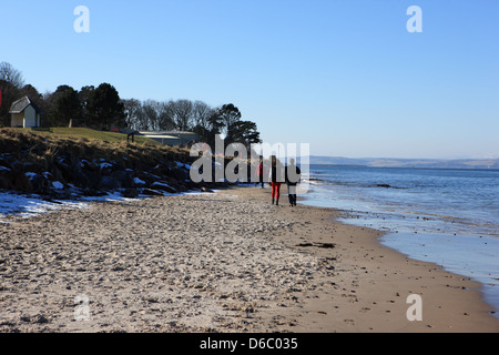 La gente camminare sulla spiaggia a Nairn nelle Highlands scozzesi in un freddo ma soleggiato inverni giorno Foto Stock