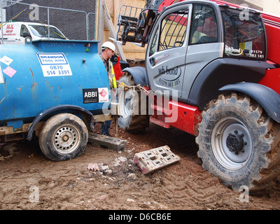 Sito in costruzione lavoratore riempiendo il suo grande macchina con combustibile di diesel sul sito. Aprile 2013 Foto Stock