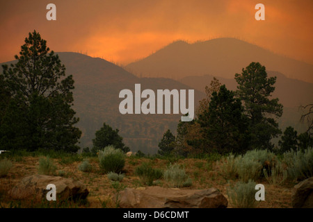 Questa foto cattura un tramonto pieno di fumo sulle montagne Jemez nel New Mexico, dopo l'incendio del 2011 nei pressi del Los Alamos National Laboratory. Essa è un drammatico richiamo all'impatto delle catastrofi naturali sulle strutture scientifiche. Foto Stock