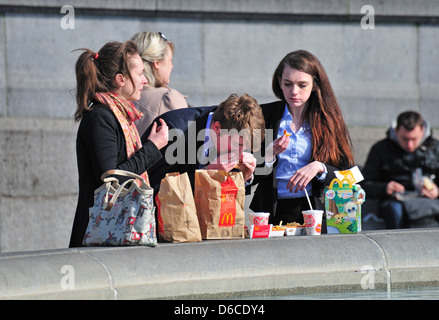 Londra, Inghilterra, Regno Unito. I giovani lavoratori di mangiare fast food per pranzo in Trafalgar Square Foto Stock